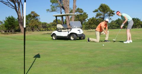 Friends playing golf on scenic course under blue sky