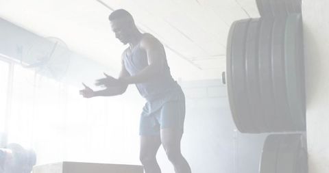 Male athlete clapping before plyo box jump in industrial gym strength workout