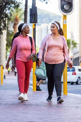 African american women walking together in pink activewear urban fitness friendship