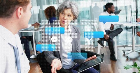 Senior businesswoman leading discussion with tablet, gesturing during modern office meeting