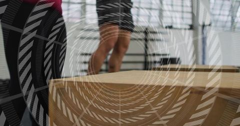 Athlete preparing plyo box jump while trainer spotting on wooden box in industrial gym