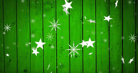 Christmas stars falling on green wooden background