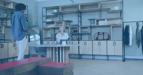 Retail consultant assisting customer at minimalist boutique desk with tablet