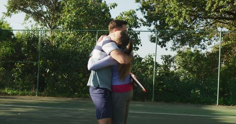 Couple Embracing on Tennis Court After Match Celebration
