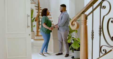 Happy Couple Embracing New Home Standing Near Staircase
