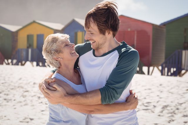 Happy mother embracing her son at beach during sunny day