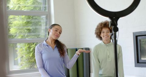 Fitness creators presenting home workout session with ring light, yoga mats, natural light