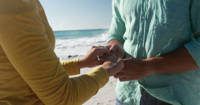 Mid section of caucasian couple holding hands on beach by seaside with copy space. Lifestyle, vacation, summer, happiness, wellbeing concept, unaltered.