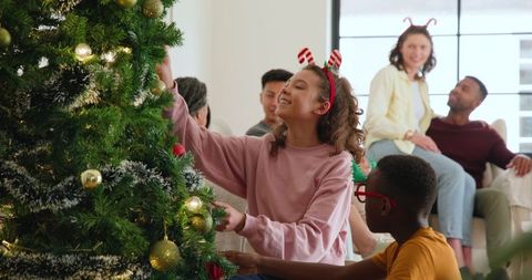 Family Decorating Christmas Tree Together in Cozy Living Room