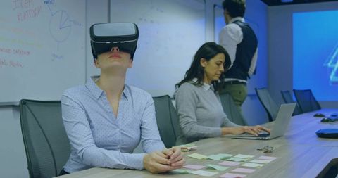 Businesswoman Wearing Virtual Reality Headset During Team Brainstorming in Modern Boardroom