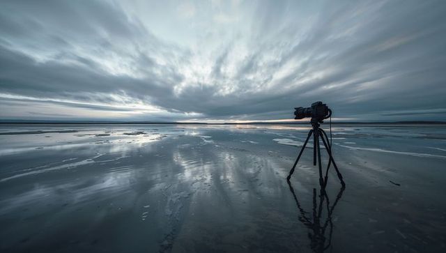 Dslr on tripod capturing wide seascape reflections at low tide under dramatic cloudy sky