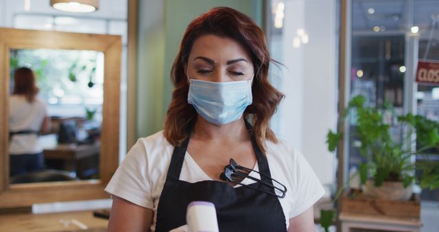 Female hairstylist in salon wearing face mask and apron - Download Free Stock Images Pikwizard.com