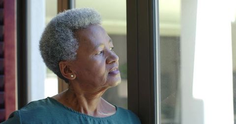 Senior african american woman gazing through window, contemplative elder portrait in daylight