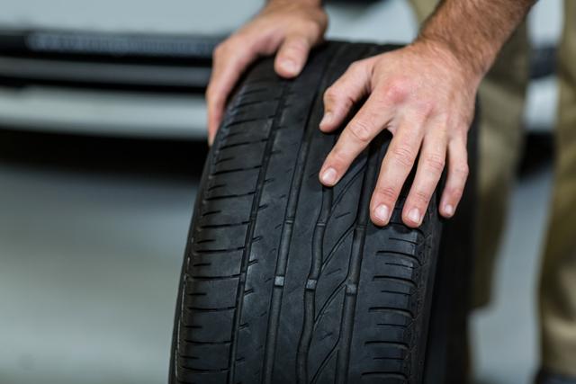 Hands of mechanic touching tyres in repair garage