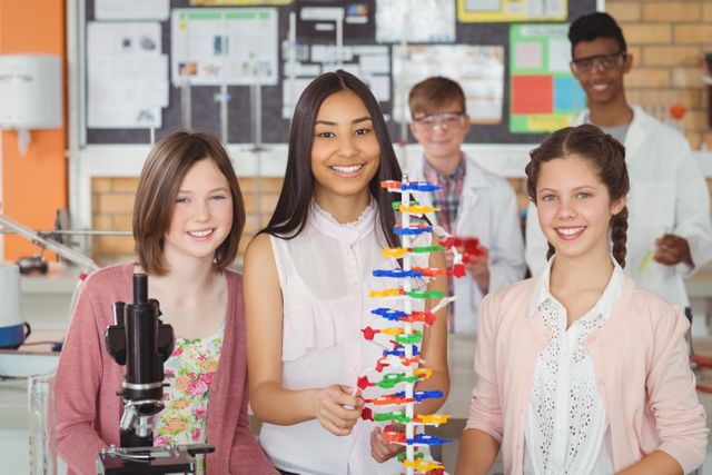 Portrait of happy students experimenting molecule model in laboratory at school