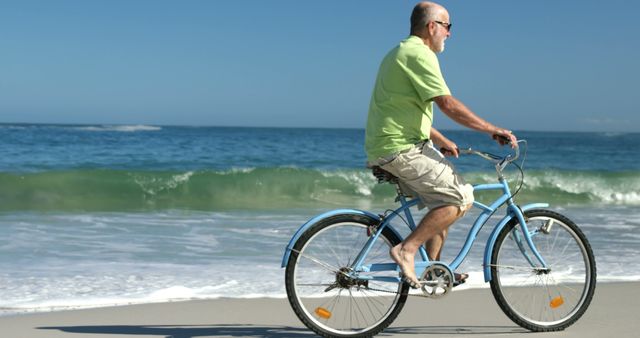 Senior man riding bicycle along beach shoreline. Perfect for depicting active lifestyle in older age, wellness, and leisure during retirement. Suitable for travel, health promotions, and content focused on outdoor activities and beach vacations.