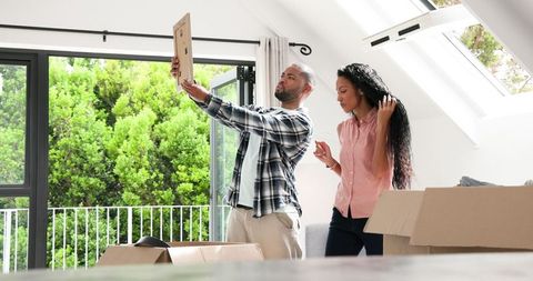 Couple unpacking in sunlit modern home with big windows