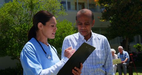 Doctor discussing medical report with senior man in garden