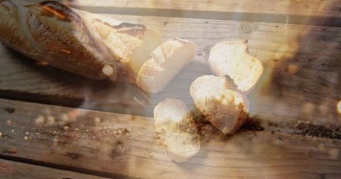Sliced french baguette illuminated by sun flare on rustic table
