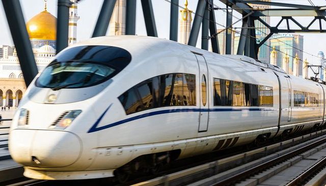 High-speed train crossing truss bridge reflecting golden dome in modern cityscape