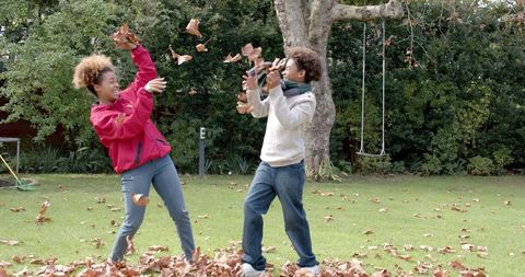 Joyful African American Mother and Son Playing with Autumn Leaves
