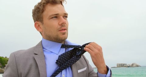 Businessman Loosening Necktie by Beach on Overcast Day - Download Free Stock Images Pikwizard.com