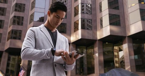 Young Businessman Checking Smartphone in Urban Setting