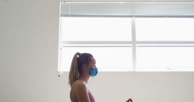 Woman Meditating Indoors Wearing Face Mask By Window - Download Free Stock Images Pikwizard.com