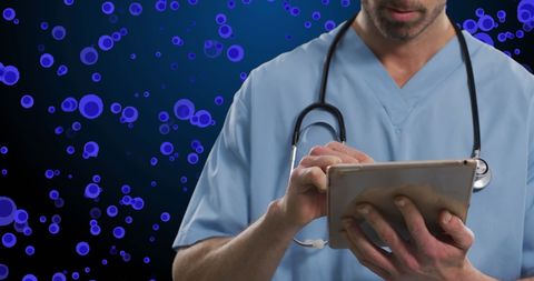 Male doctor using tablet with blue cells in background