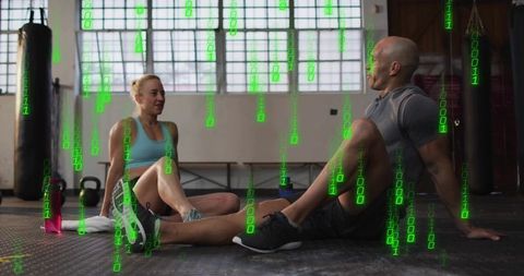 Couple resting after workout in boxing gym with green binary overlay, fitness tech concept