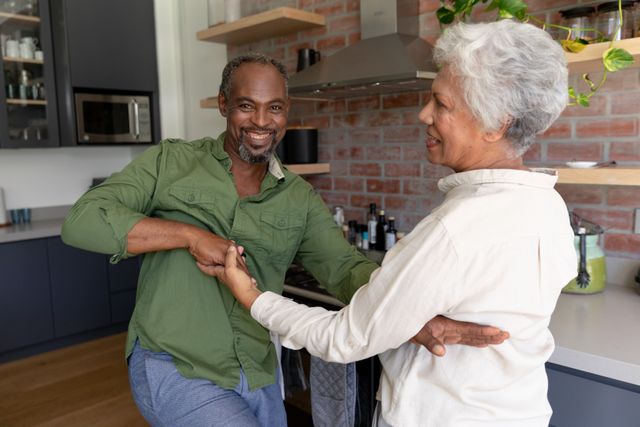 Senior African American couple enjoying their time at home together, dancing and smiling, social distancing and self isolation in quarantine lockdown during coronavirus Covid19 epidemic.