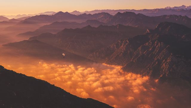 Sunrise over a magnificent mountain range covered in early morning fog. Perfect for use in travel blogs, outdoor adventure promotions, and nature-themed presentations.