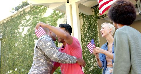 Soldier Greeting Friends with American Flags Outdoors