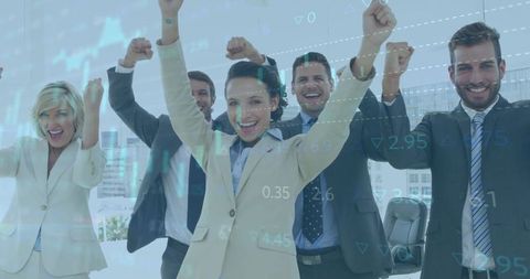Celebrating corporate team raising fists with financial data overlay in modern office