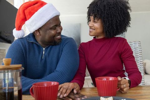 African american couple sharing coffee and smiling on cozy holiday morning
