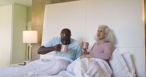 Senior Couple Relaxing in Bedroom with Morning Coffee