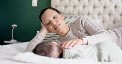 African American Mother Gently Bonding with Infant on Bed