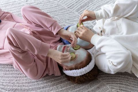 Friends enjoying at-home spa with green face masks and cucumber slices