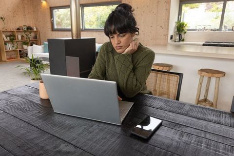 Woman Working on Laptop in Cozy Modern Cabin Interior