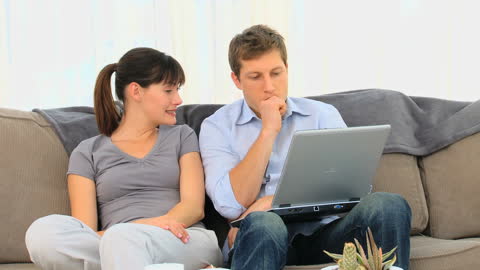 Young Couple Relaxing on Couch with Laptop