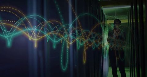 IT technician standing in datacenter corridor using handheld device with neon waveform