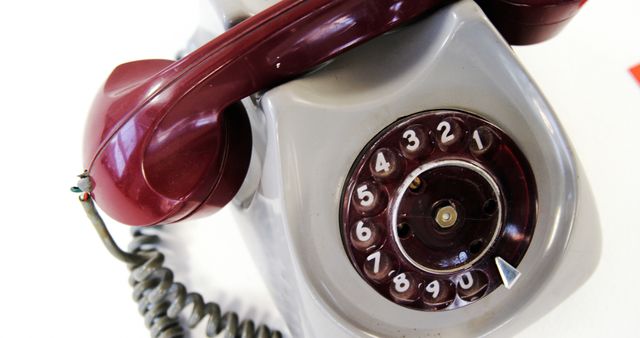 Vintage rotary telephone with burgundy receiver and grey dial, presenting classic design and nostalgic value. Ideal for presentations on retro technology, history of communication, or vintage decor projects.