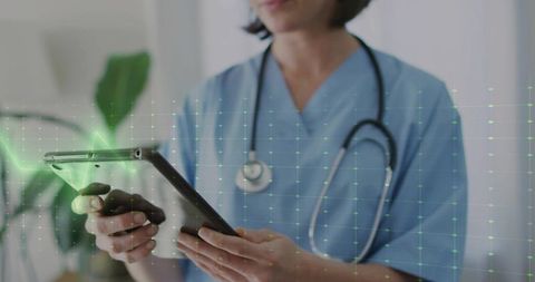 Clinician using tablet with stethoscope and green holographic medical data overlay
