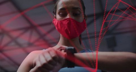 Female athlete wearing red face mask checking smartwatch in neon gym wearable fitness tech