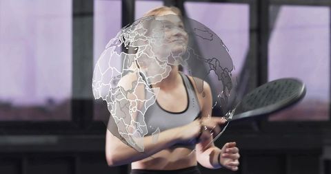 Blonde athlete swinging paddle with holographic globe overlay on indoor sport court