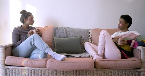 Diverse Friends Relax on Cozy Couch with Mugs in Hand
