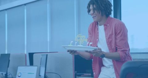 Office worker offering birthday cake in open-plan workspace celebrating coworker