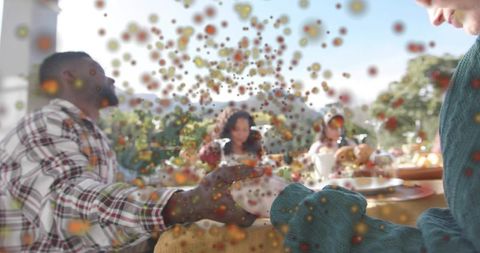 Alfresco family gathering passing bread across sunlit patio table with festive bokeh overlay
