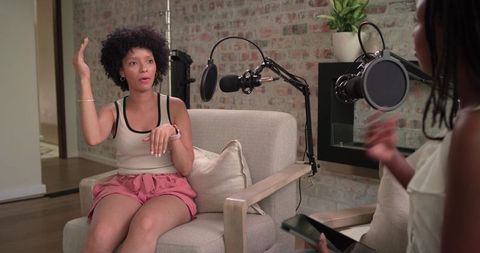 African american women recording conversational podcast in modern studio with microphones