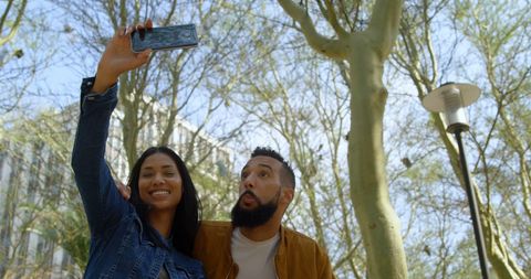Mixed couple taking selfie in outdoor urban park